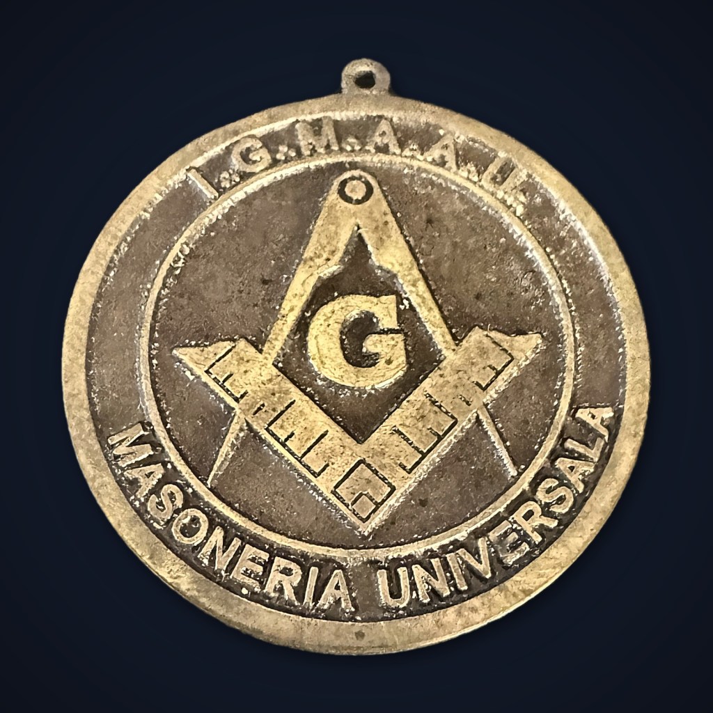 Medalie de bronz cu toartă, echerul și compasul cu litera G, inscripțiile I.G.M.A.A.U. și Masoneria Universală